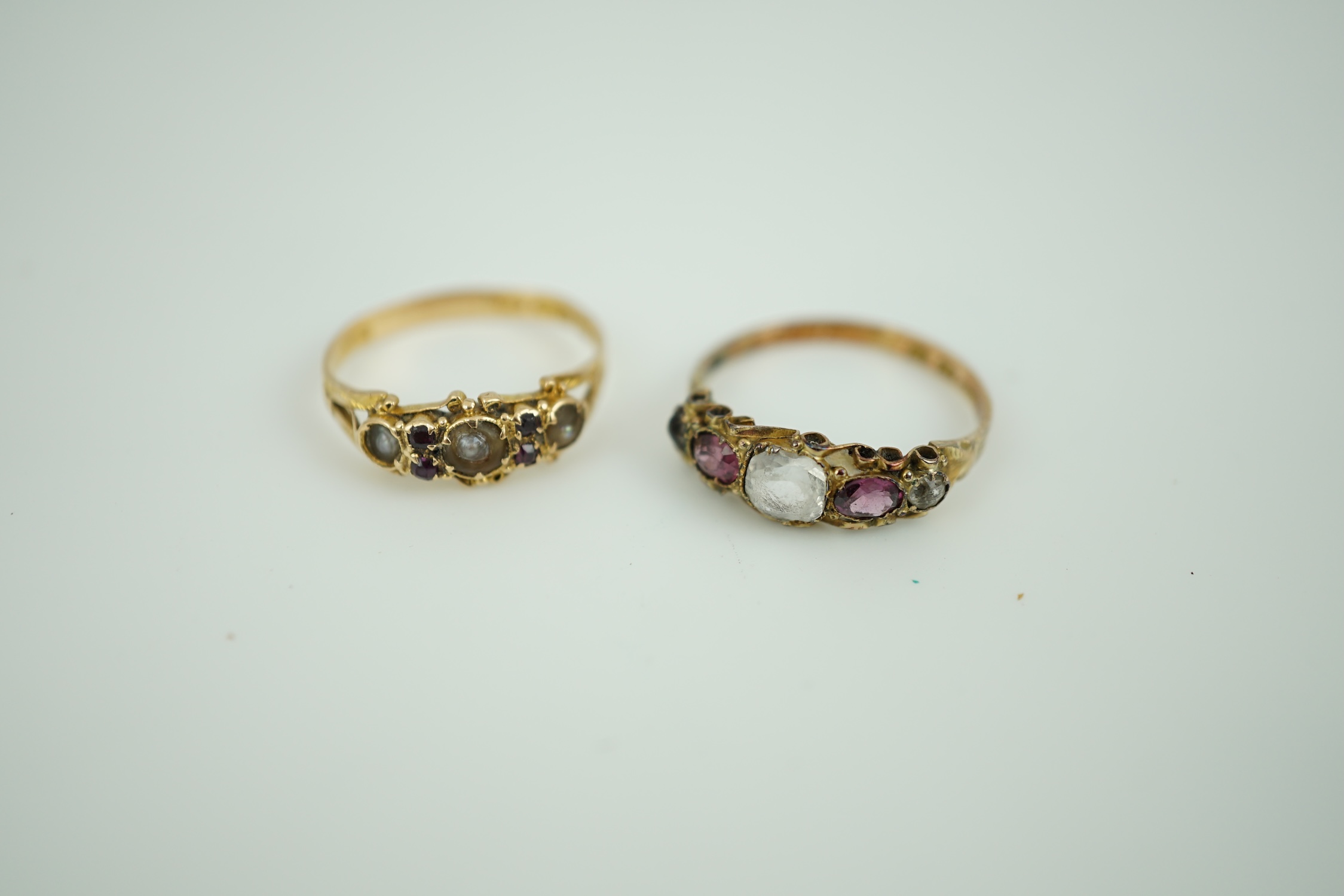 A late Victorian 15ct gold, split pearl and garnet cluster set ring, size N/O and a similar 12ct gold, paste and garnet cluster set ring.